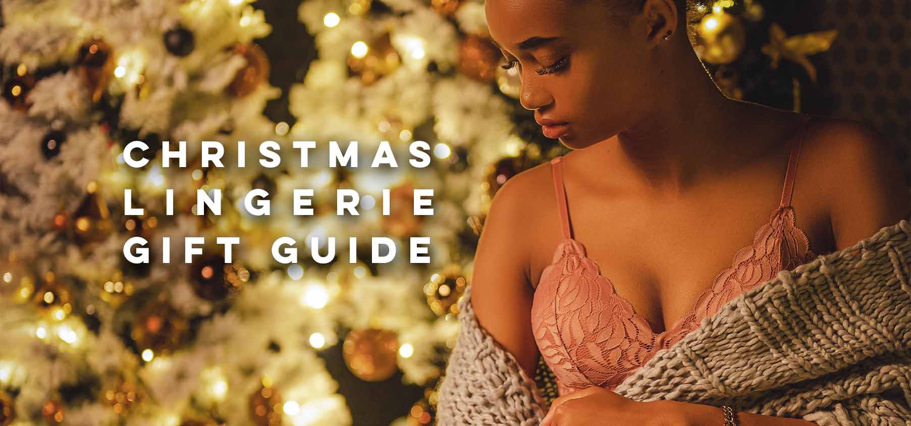A woman wearing a delicate pink lace bra with thin straps wrapped in a textured gray knit shawl for christmas gift ideas.
