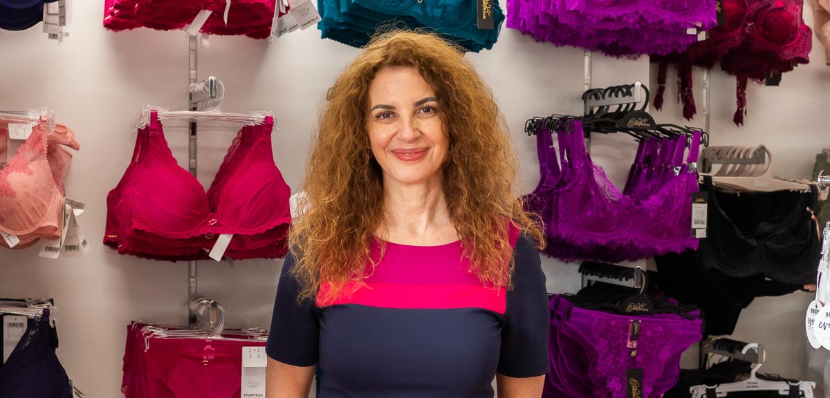 Woman with curly auburn hair wearing a navy and magenta color-block top in article about Tracey the trusted bra expert.