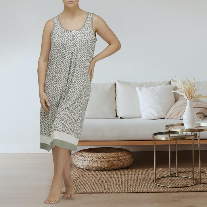 A woman wears a sleeveless knee-length nightgown with a subtle geometric pattern in muted gray from YUU Sleepwear.