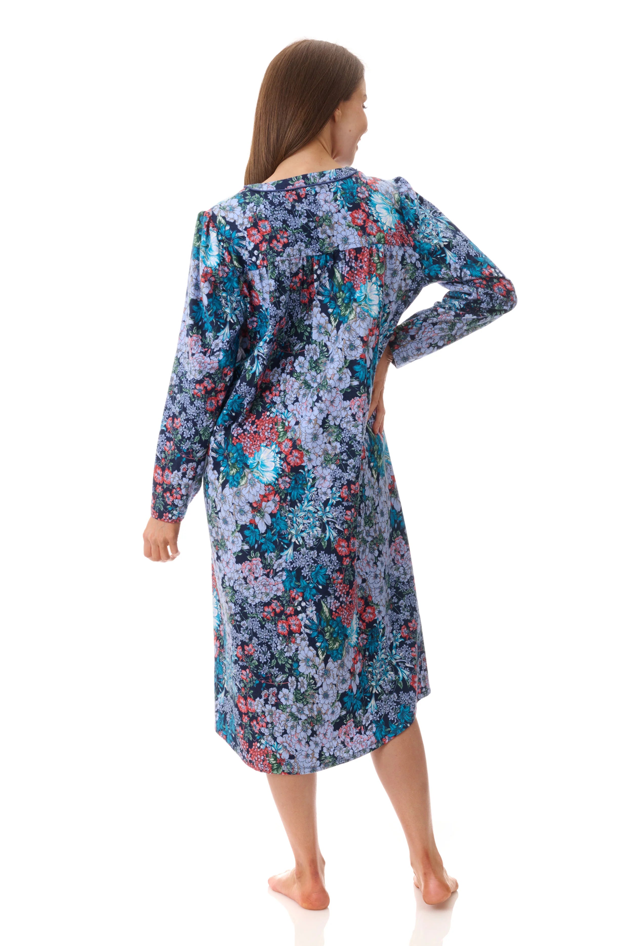 A woman wearing a frida mid nightie long-sleeved knee-length floral nightgown in blue purple and pink on soft fabric