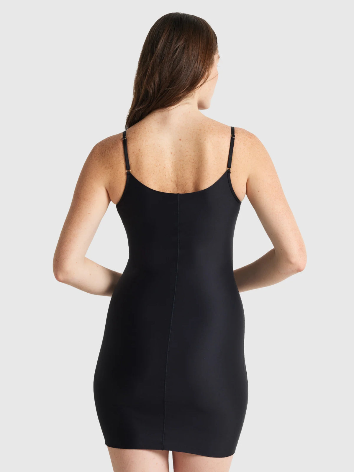 The slip edit slip black form-fitting dress with thin straps and central seam down the back shown from behind