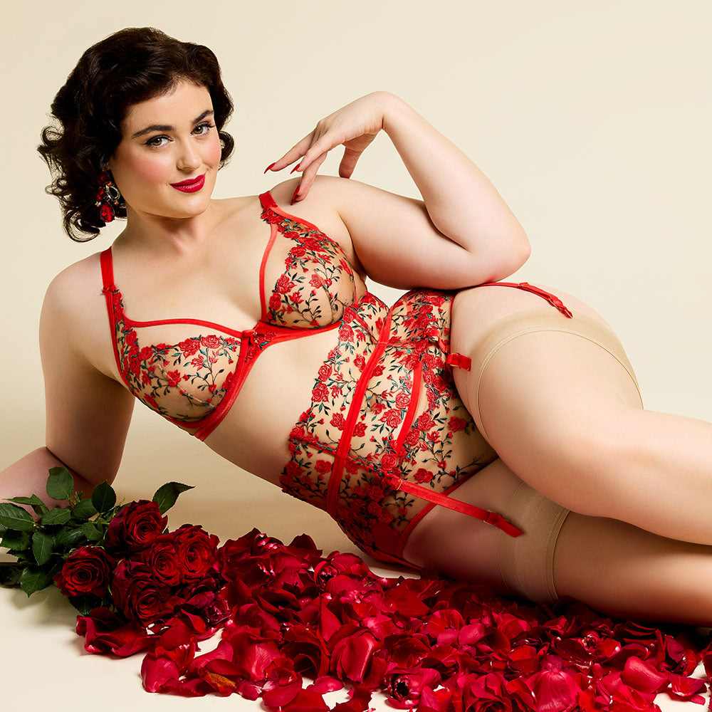 Woman in sexy red lingerie surrounded by roses on a beige background