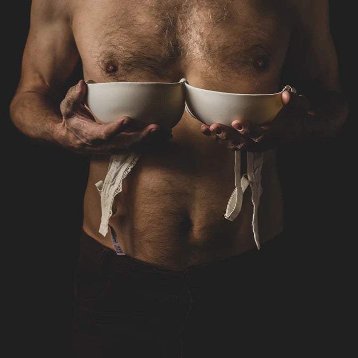 Man with hairy chest holding a bra