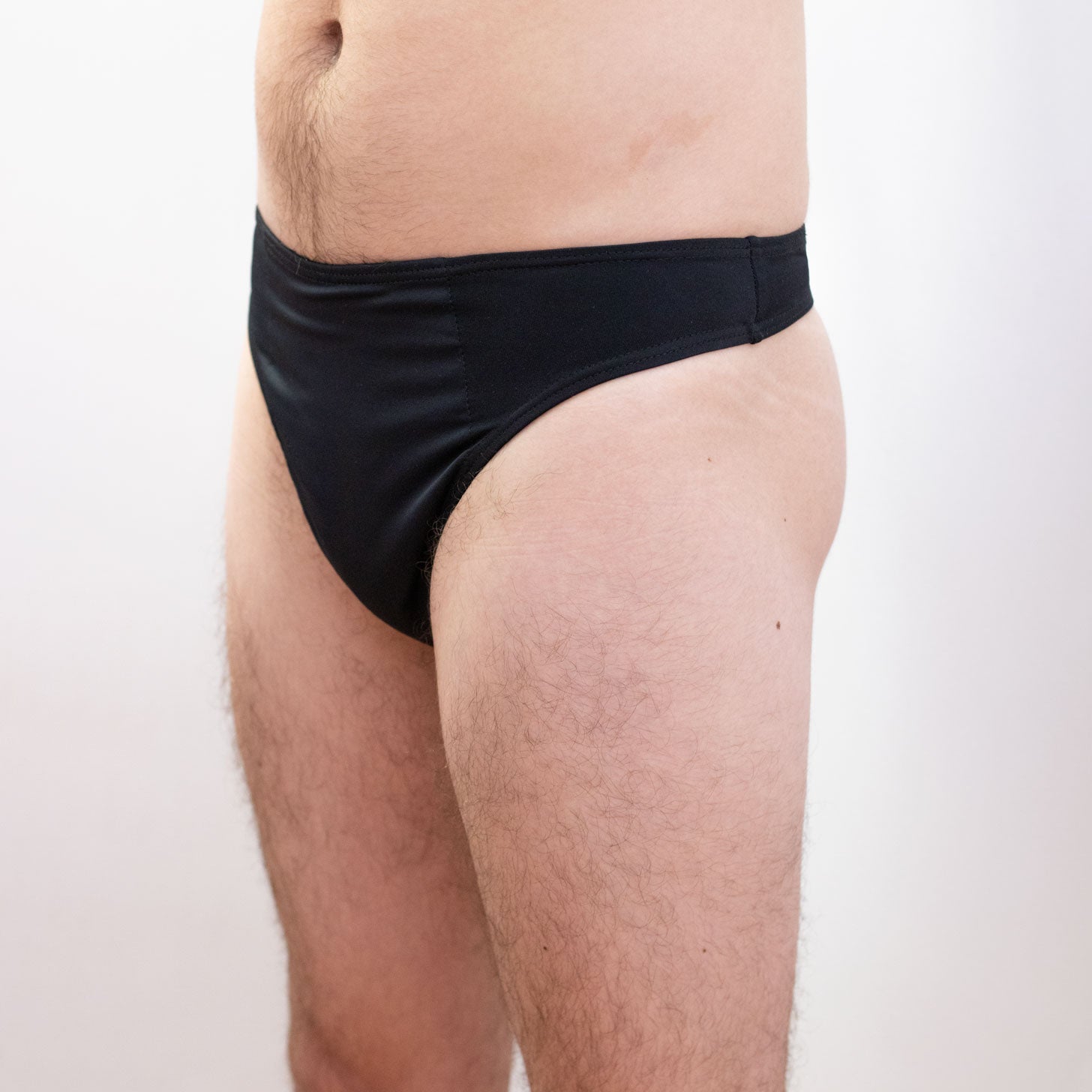 Person wearing black tucking briefs on a white background