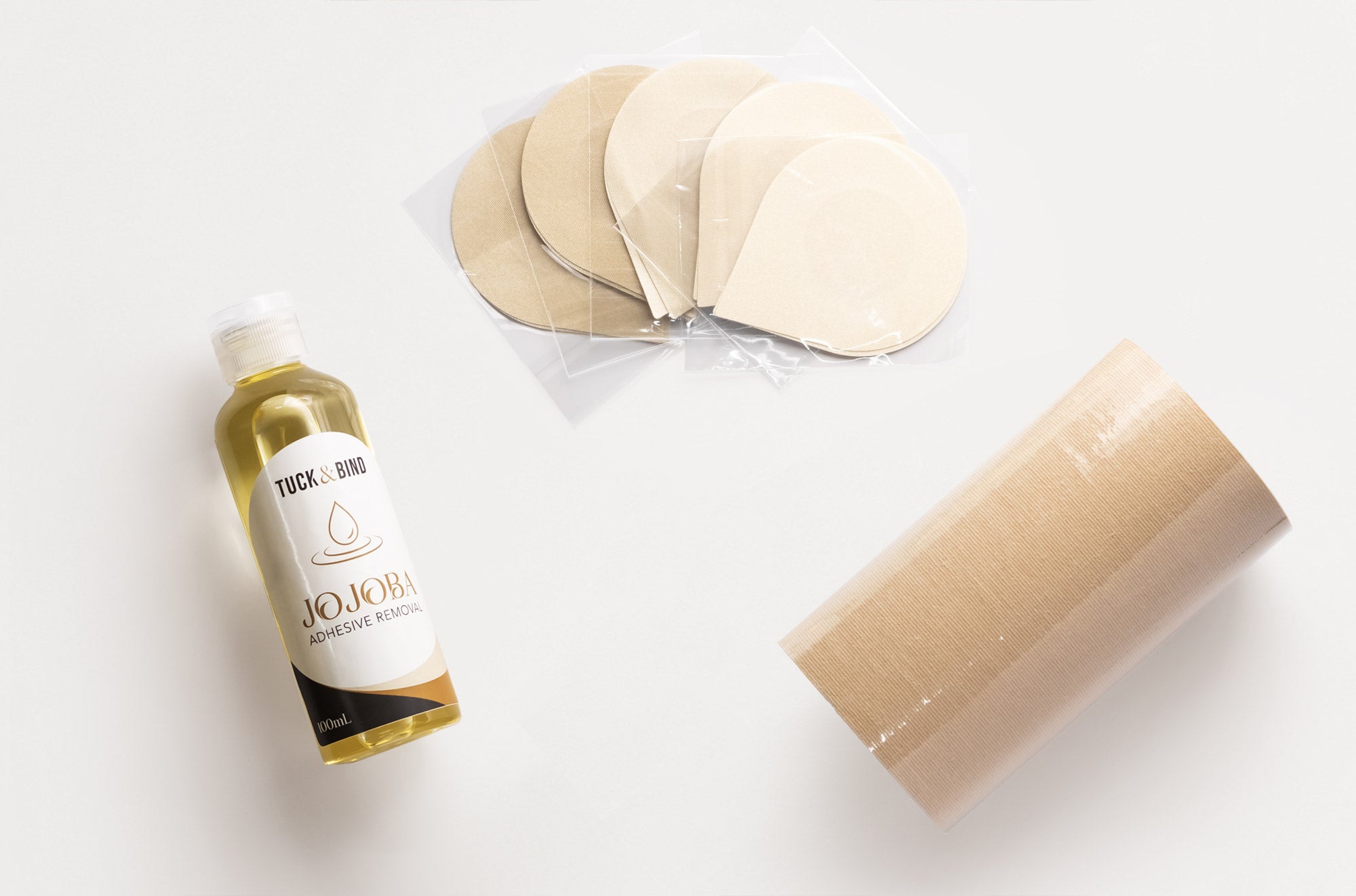 Bra accessories products including a adhesive removal bottle, nipple covers, and beige breast tape on a white background