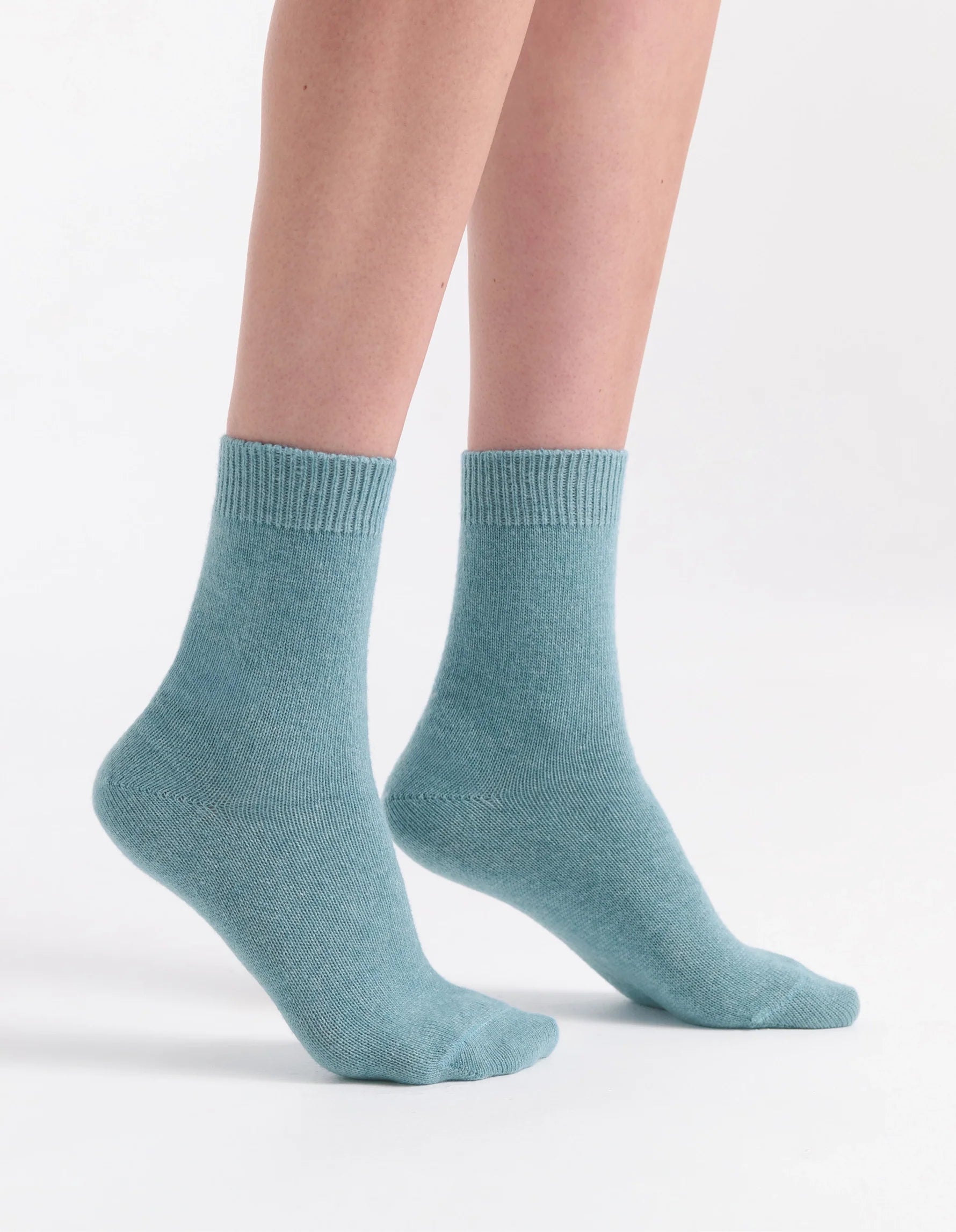A pair of soft light teal pina crew ankle socks with ribbed cuff and simple knit design