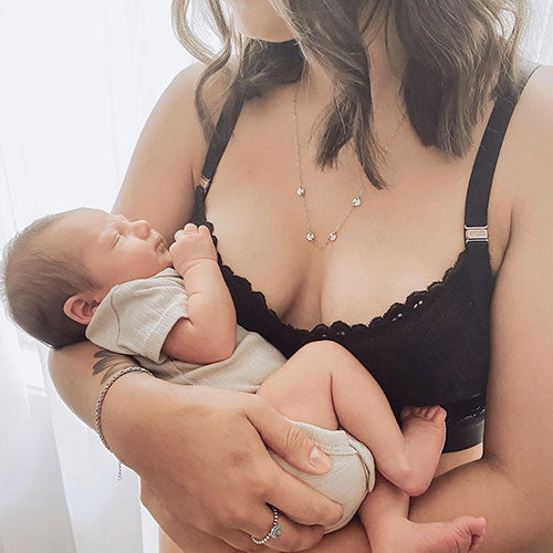 Woman wearing black HotMilk maternity bra while holding a baby