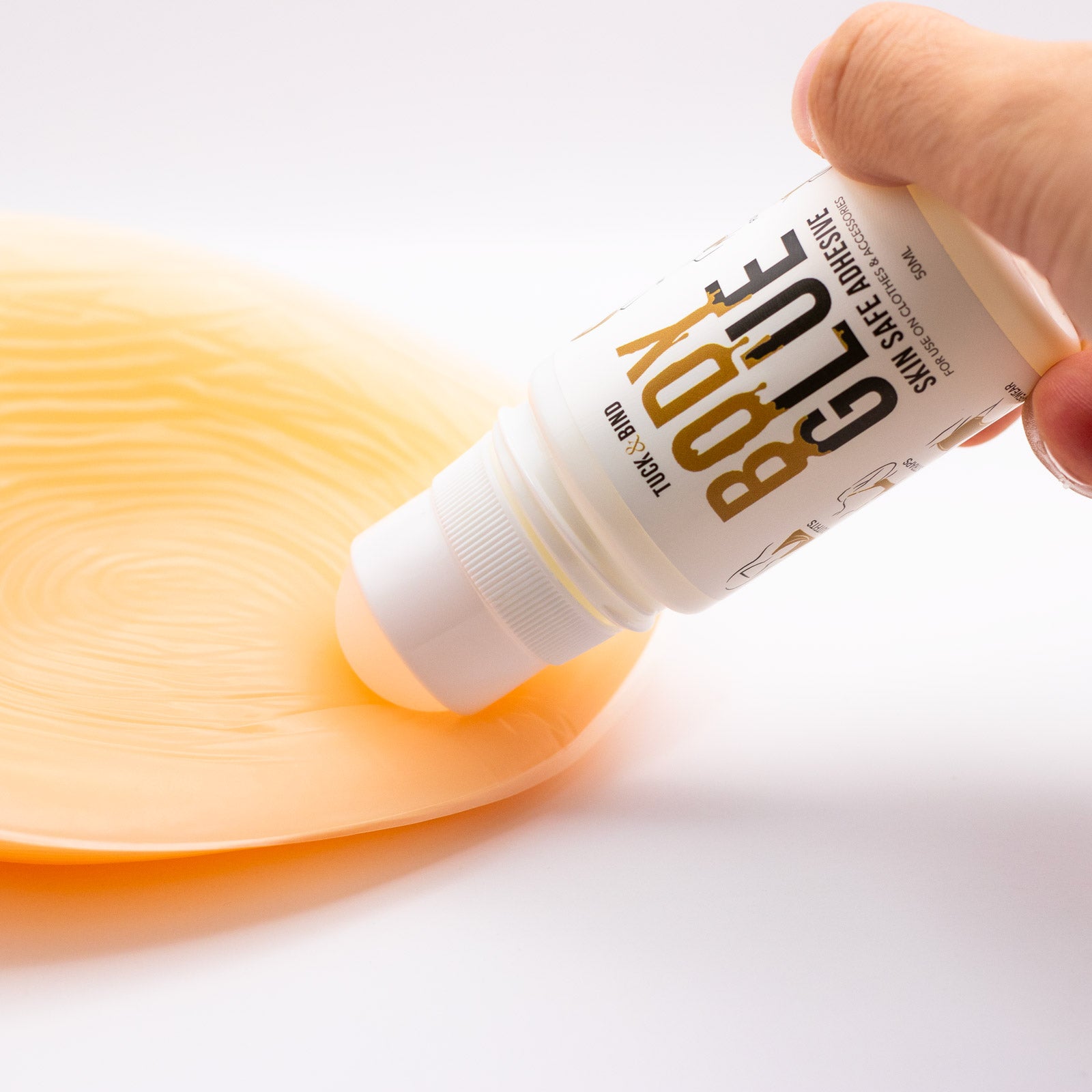 A white bottle of gloxy body glue 50ml with gold lettering labeled skin safe adhesive for clothes and accessories