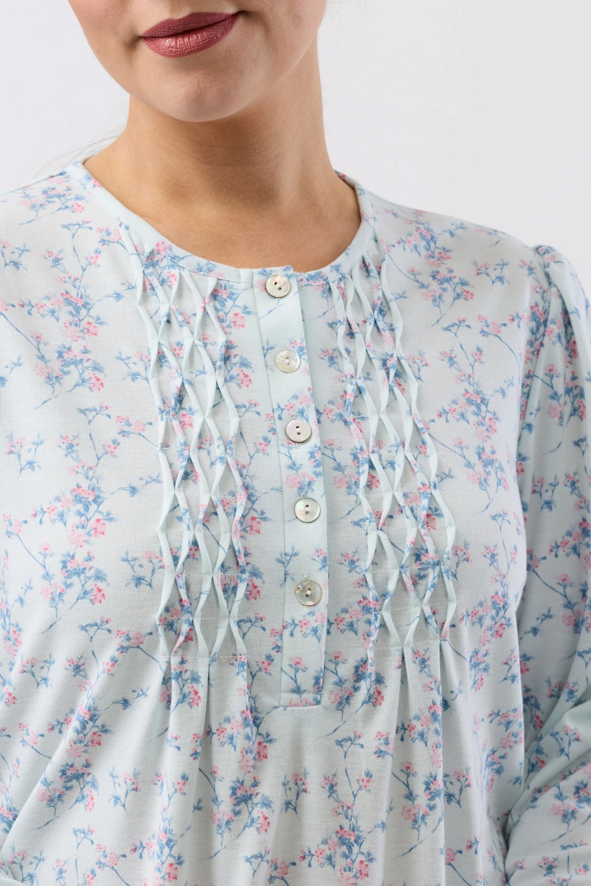 A delicate light blue cherry blossom nightie blouse with subtle pink and green floral pattern and pleated front detailing