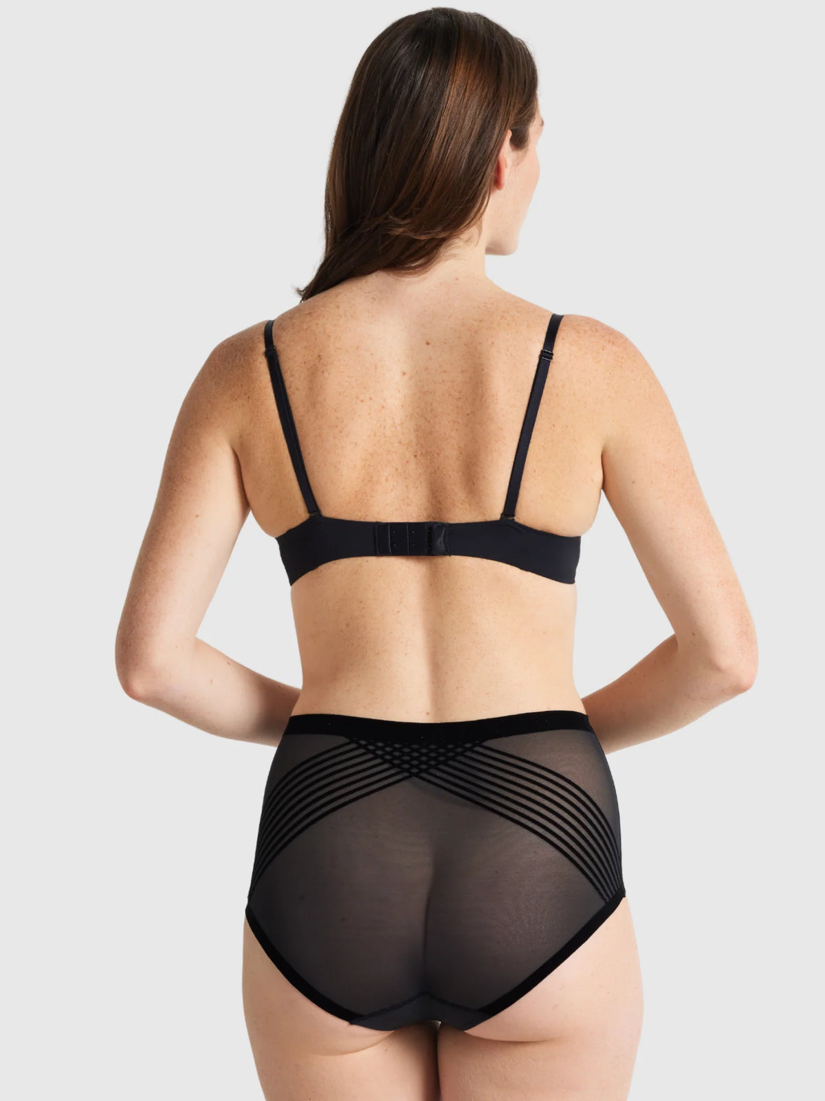 Black sheer high waisted briefs with elastic straps and crisscross design shown from the back side