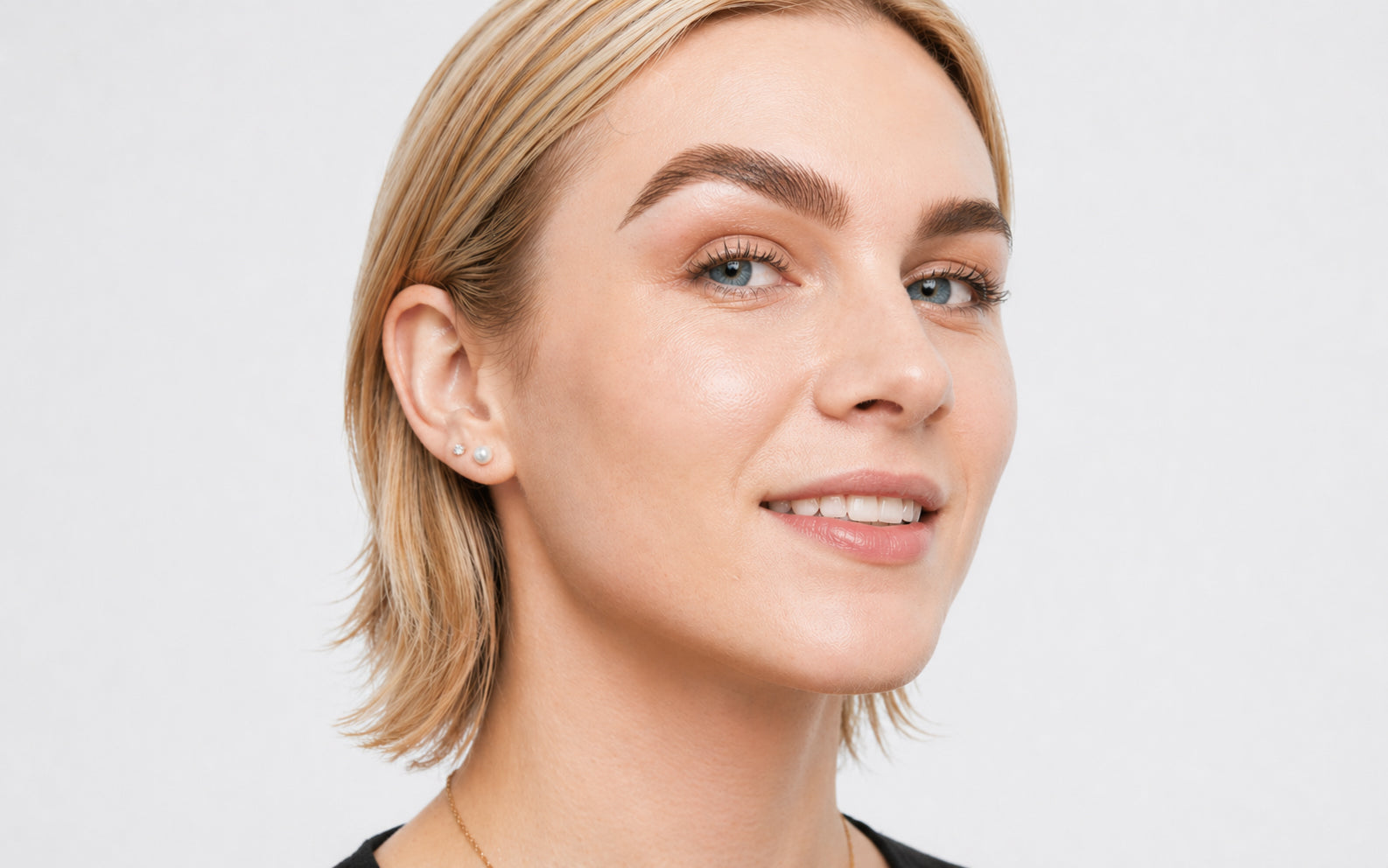 A woman wearing a delicate gold chain necklace shown with face lift tape 40 pack for skin tightening