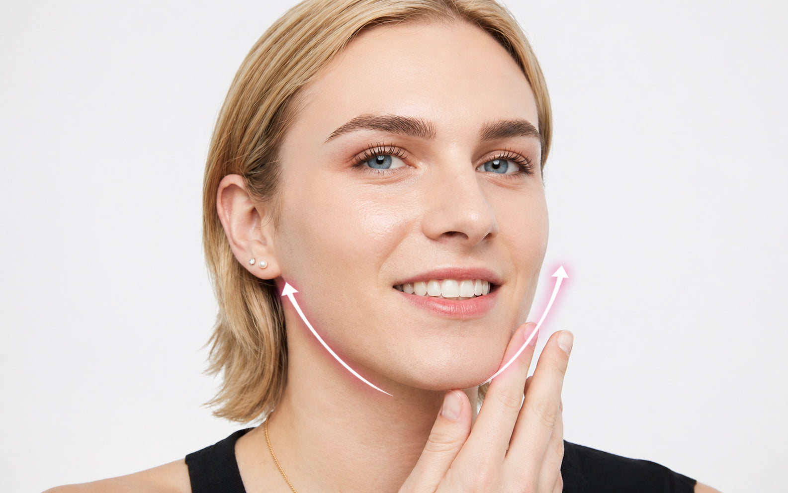 A woman with blonde hair and blue eyes gently touches her jawline wearing a black top using face lift tape 40 pack