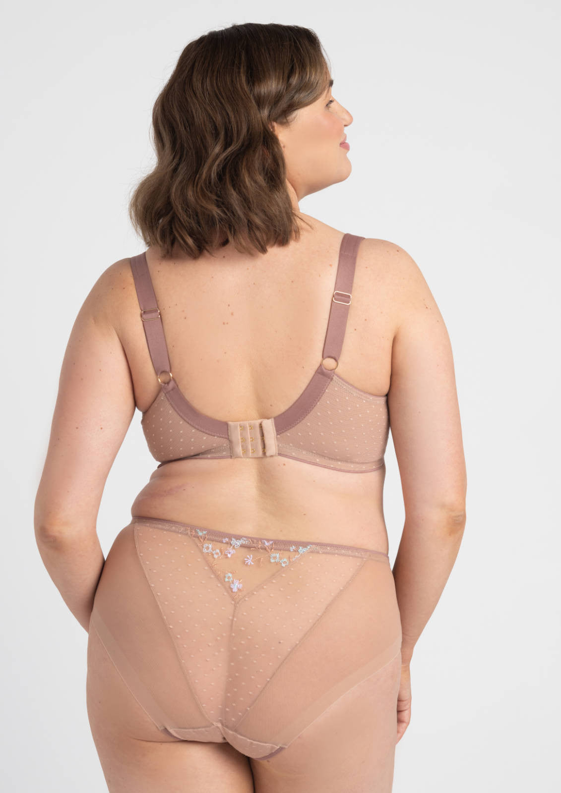 A taupe-colored sheer lace bra with delicate floral embroidery and adjustable straps from the margaret figs brief collection