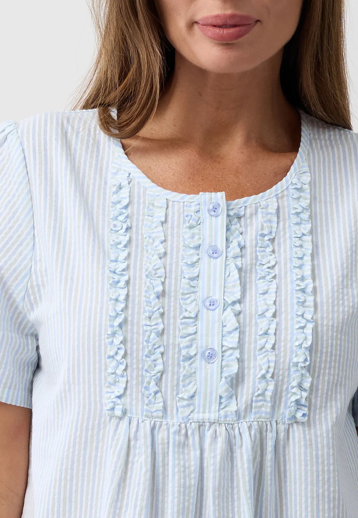 A light blue and white striped nightie with delicate ruffled trim along the neckline and front button placket